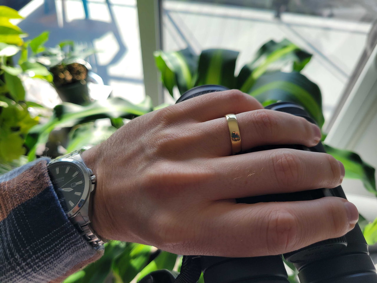 Argolla de matrimonio de oro liso en una mano bajo luz natural