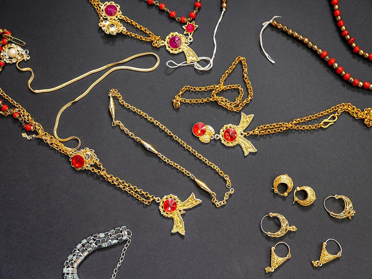 Colección surtida de collares, cadenas, aretes y joyería decorativa sobre tela oscura