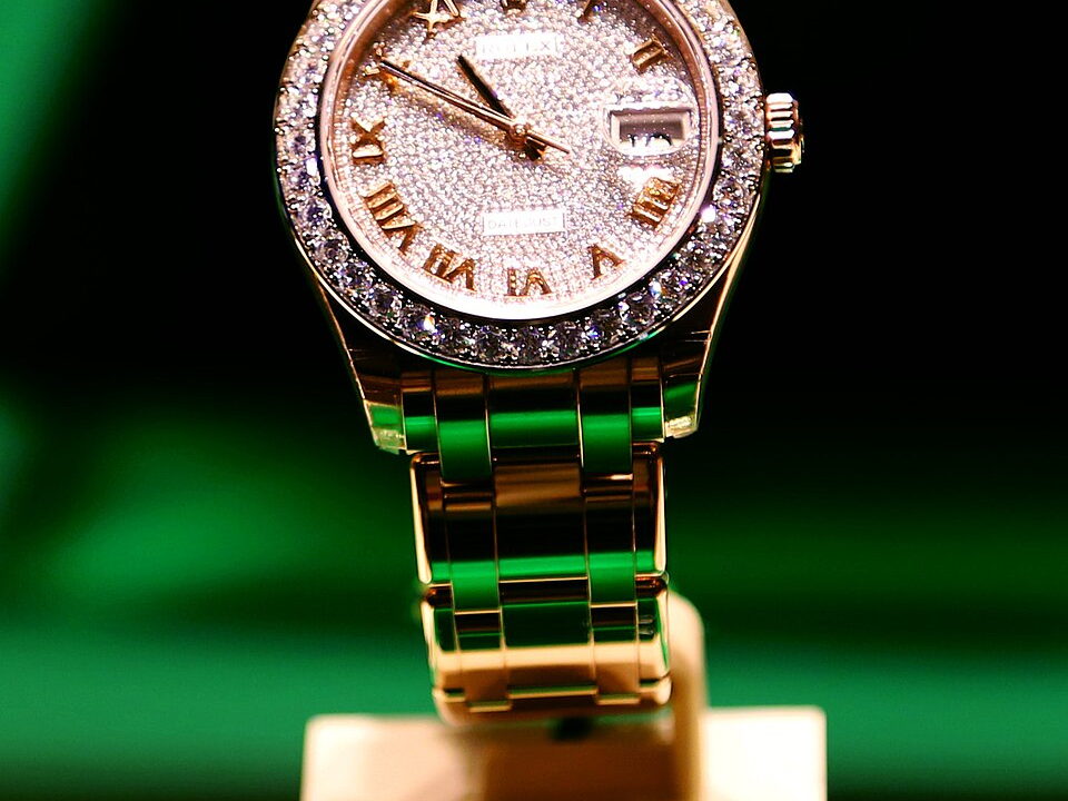 Fotografía cercana de un reloj Rolex con diamantes sobre una exhibición verde oscura